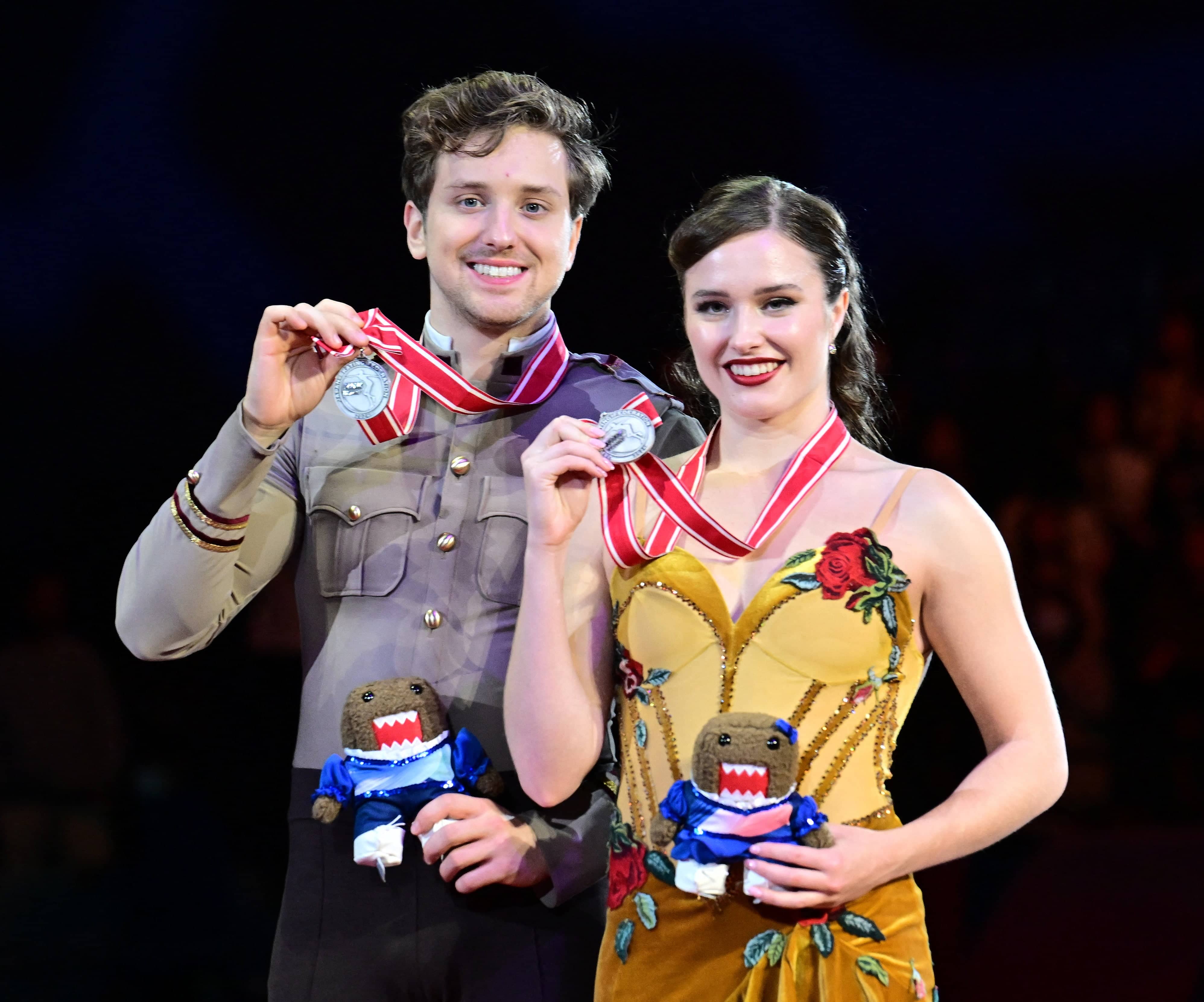 Anthony Ponomarenko and Christina Carreira hold up their silver medals on the podium and smile at NHK Trophy.